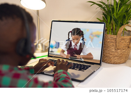 Rear view of african american boy using laptop while having a video call with biracial girl 105517174