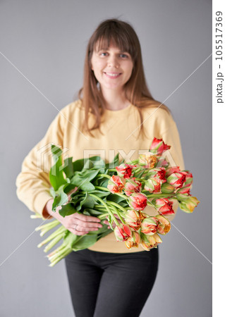 Tulip Gudoshnik in woman hand. Spring bouquet of red tulips in hands. Bunch of fresh cut spring flowers 105517369