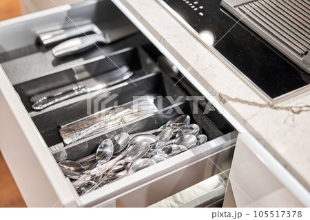 Kitchen utensil cutlery drawer organizer tray with simple set of tools, minimalist order. Open drawer with different utensils and folded towels. Order in kitchen. Kitchen furniture store. 105517378