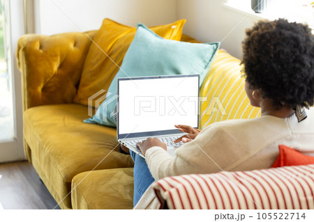 Plus size african american woman using laptop with copy space on screen at home 105522714