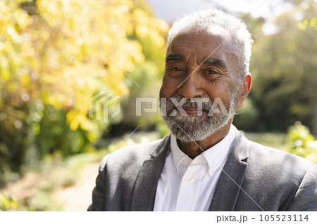 Portrait of happy senior biracial man smiling in sunny garden at home, copy space 105523114