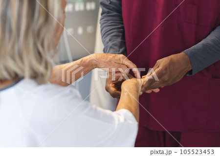 Midsection of african american male doctor examining hands of senior female caucasian patient Midsection of african american male doctor examining hands of senior female caucasian patient 105523453