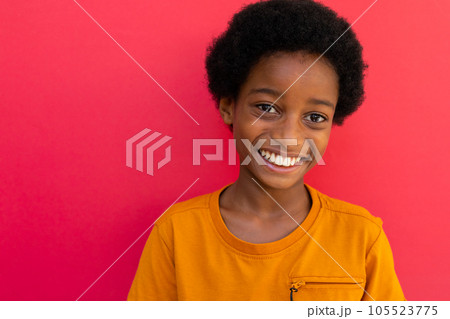 Portrait of happy biracial schoolboy wearing yellow tshirt over pink background Portrait of happy biracial schoolboy wearing yellow tshirt over pink background 105523775