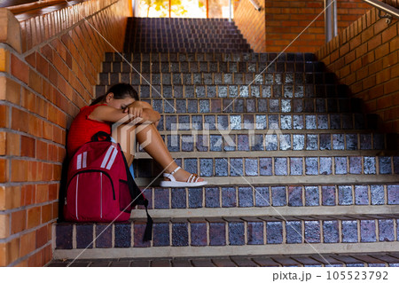 Sad caucasian schoolgirl with school bag sitting on stairs at school, copy space Sad caucasian schoolgirl with school bag sitting on stairs at school, copy space 105523792