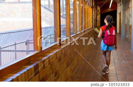 Caucasian schoolgirl walking with school bag and books at school corridor, copy space 105523833