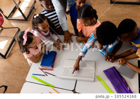 High angle view of diverse male teacher using laptop teaching children in elementary school class 105524168