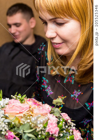 Mothers day. A woman admires a gorgeous bouquet from son. The blonde looks at flower arrangement. Congratulations on Women's Day, Mother's Day, Birthday. Vertical photography. Selective focus 105525346