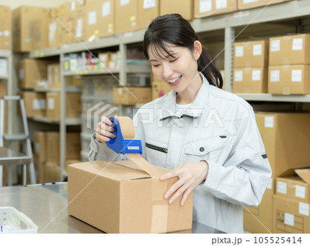 物流センターの倉庫で段ボールにテープを貼る若い女性スタッフ 物流センターの倉庫で段ボールにテープを貼る若い女性スタッフ 105525414