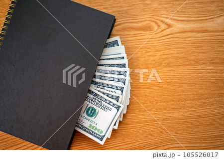 Still Life of hundred Dollar Bank Notes in personal notebook on working desk with copy space 105526017