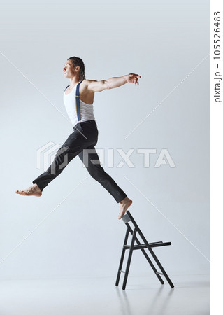 Creative portrait of handsome mature man with muscular body posing on chair against grey studio background Creative portrait of handsome mature man with muscular body posing on chair against grey studio background 105526483