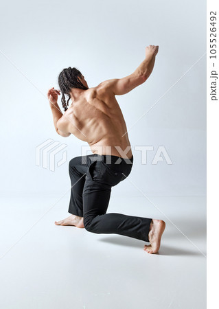 Athletic man posing in motion shirtless, in pants against grey studio background. Healthy, strong, relief body Athletic man posing in motion shirtless, in pants against grey studio background. Healthy, strong, relief body 105526492