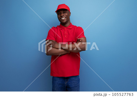 handsome young courier american man wearing corporate clothing consisting of a red cap and t-shirt handsome young courier american man wearing corporate clothing consisting of a red cap and t-shirt 105527763