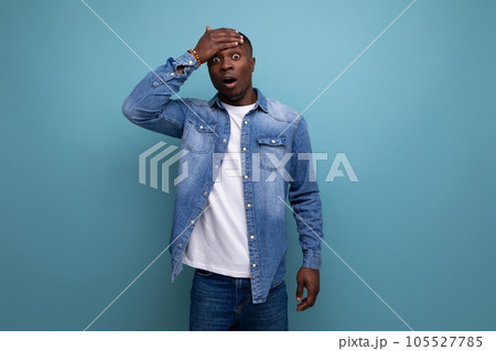 surprised young attractive african man dressed in denim jacket and t-shirt on backgrounds with copy 105527785