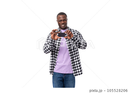 portrait of an attractive dark skinned man in a plaid shirt and jeans showing a plastic card in his 105528206