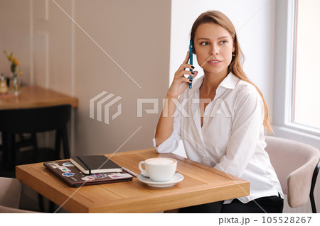 Portrait of lady speak by phone during break in cafe. Woman have rest and drink coffee Portrait of lady speak by phone during break in cafe. Woman have rest and drink coffee 105528267