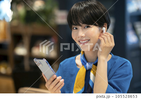 イヤホンをつけてスマートフォンを持った若い女性　撮影協力：Creadisce（丸善雄松堂株式会社） 105528653