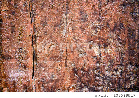 Old wooden surface of red color with various flaws and defects, dents, cracks, some burnt areas 105529917