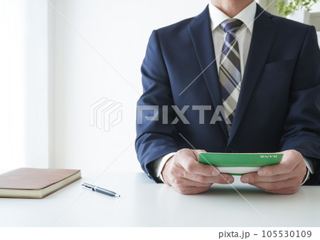 通帳を見るビジネスマン 通帳を見るビジネスマン 105530109
