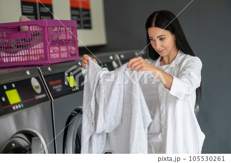 Young woman doing his weekly washing in a laundromat. 105530261