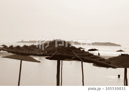 Sepia-Toned Straw Umbrellas on Beach Overlooking the Ocean. Sepia-Toned Straw Umbrellas on Beach Overlooking the Ocean. 105530831