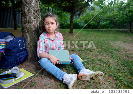 Primary school student, cute girl looking at camera with tears on eyes, having school problems and learning difficulties Primary school student, cute girl looking at camera with tears on eyes, having school problems and learning difficulties 105532591