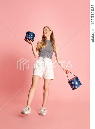 Happy young pretty blonde girl, student wearing modern casual style clothes go with boxes of presents over pink background. Happy young pretty blonde girl, student wearing modern casual style clothes go with boxes of presents over pink background. 105532885