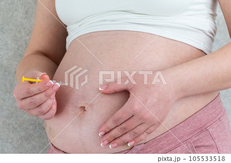 Blood thinners concept. Pregnant woman making injection in stomach Blood thinners concept. Pregnant woman making injection in stomach 105533518