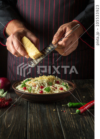 The chef adds cheese on spaghetti with vegetables in a plate. Menu or recipe for a delicious lunch for a hotel or restaurant. Delicious pasta with vegetables and spices The chef adds cheese on spaghetti with vegetables in a plate. Menu or recipe for a delicious lunch for a hotel or restaurant. Delicious pasta with vegetables and spices 105533923