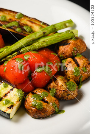Assorted grilled vegetables with pesto sauce on a white plate. 105534202