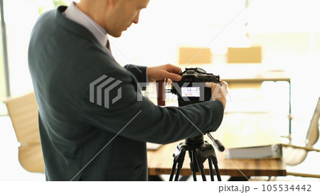 Photographer in studio adjusts settings of camera Photographer in studio adjusts settings of camera 105534442