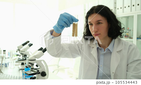 Male chemist scientist holding test tubes with grains in laboratory closeup Male chemist scientist holding test tubes with grains in laboratory closeup 105534443