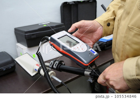 Radiation detector testing. Dosimetrist hands adjusting a portable gamma radiation dosimeter set on a long fixture Radiation detector testing. Dosimetrist hands adjusting a portable gamma radiation dosimeter set on a long fixture 105534846