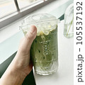 hand putting green peas into glass matcha latte  105537192
