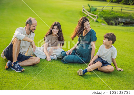 A loving family enjoying a leisurely walk in the park - a radiant pregnant woman after 40, embraced by her husband, and accompanied by their adult teenage children, savoring precious moments together 105538753