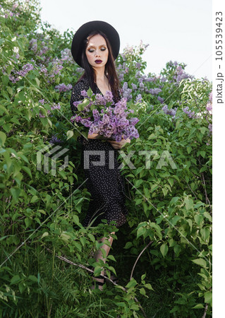 A fashionable girl with dark hair, a spring portrait in lilac tones in summer. Bright professional makeup. 105539423
