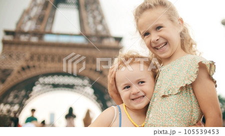 Happy little sisters hug each other and pose at the Eiffel Tower in the centre of Paris, France Happy little sisters hug each other and pose at the Eiffel Tower in the centre of Paris, France 105539453