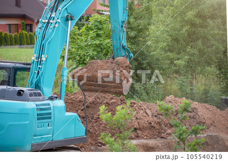 The process of working heavy construction equipment. A big blue excavator is pouring earth into a truck. Road works, reconstruction of the road surface. The process of working heavy construction equipment. A big blue excavator is pouring earth into a truck. Road works, reconstruction of the road surface. 105540219