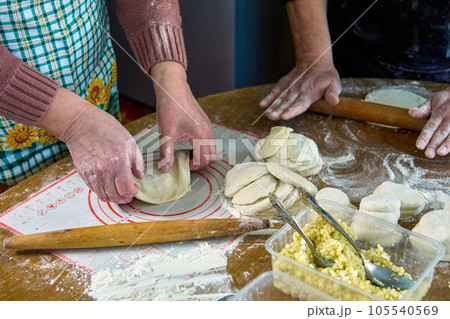 Cooking homemade pies with filling in rural house, rolling out dough, forming pie. Cooking homemade pies with filling in rural house, rolling out dough, forming pie. 105540569