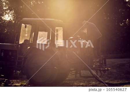Farmer adjusts sprayer on an agricultural wheeled tractor before applying chemicals to crop in field. 105540627