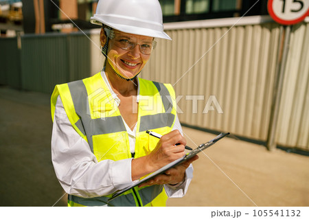 Confident female design architect making notes while examining building during construction 105541132