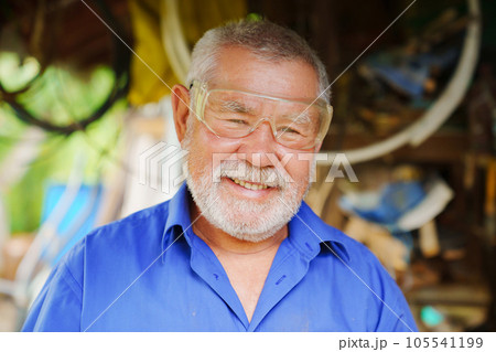 an elderly man in goggles to work with a circular saw an elderly man in goggles to work with a circular saw 105541199