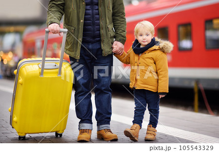 Smiling little boy and his father waiting express train on railway station platform Smiling little boy and his father waiting express train on railway station platform 105543329