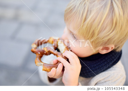 Little tourist eating traditional bavarian bread called pretzel 105543348