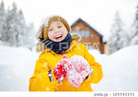 Happy preteen boy having fun playing with fresh snow during snowfall in european Alps. Child dressed in warm clothes, hat, hand gloves and scarf. Happy preteen boy having fun playing with fresh snow during snowfall in european Alps. Child dressed in warm clothes, hat, hand gloves and scarf. 105543355