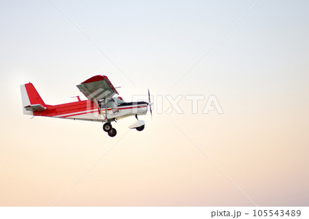 Small ultralight airplane with overhead wing and single propeller flying in sky. Such aircraft are used for recreational, sport and flight training. 105543489