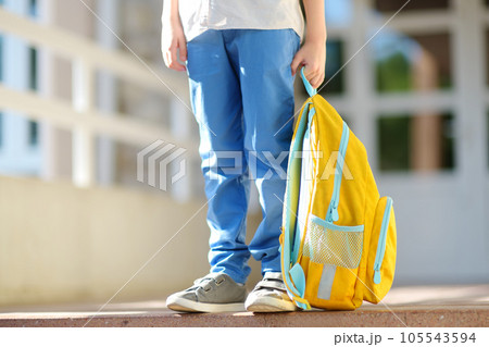 Little student with a backpack on the steps of the stairs of school building. Close-up of child legs, hands and schoolbag of boy standing on staircase of schoolhouse.Back to school concept. Little student with a backpack on the steps of the stairs of school building. Close-up of child legs, hands and schoolbag of boy standing on staircase of schoolhouse.Back to school concept. 105543594