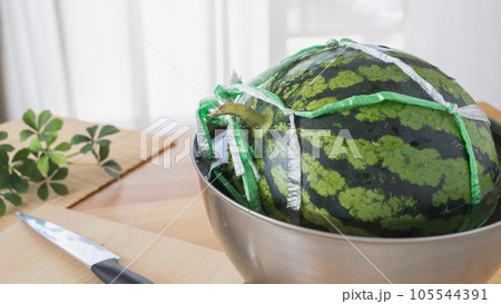 紐で縛ったスイカ｜水の入ったボウルにつける 105544391