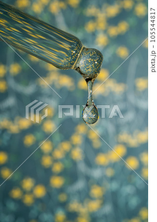 A dripping pipette with a drop of cosmetics gel. A dripping pipette with a drop of cosmetics gel. 105544817
