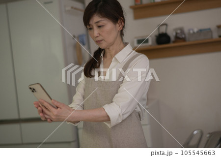 老眼でスマホを遠ざけて見る女性 105545663