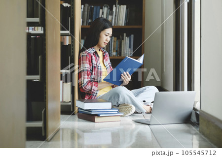 Young university student using laptop for online learning, searching and learning at library. Young university student using laptop for online learning, searching and learning at library. 105545712